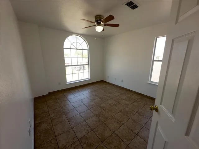 an empty room with windows and ceiling fan