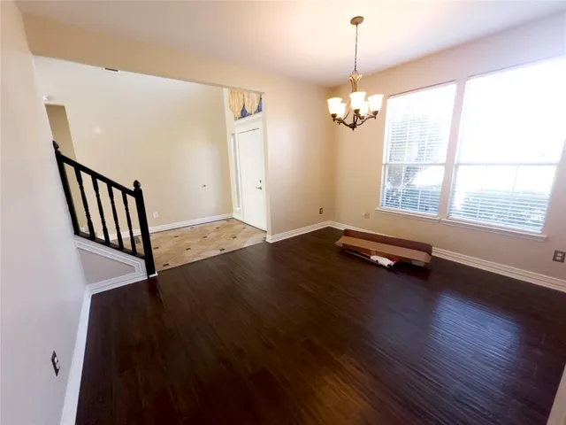 a view of an empty room with wooden floor and windows