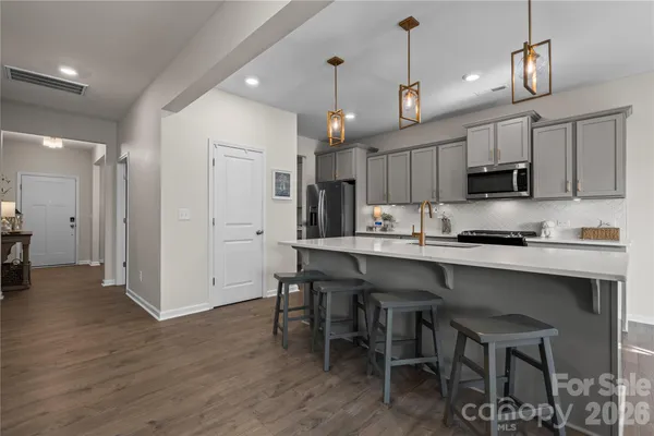 a kitchen with kitchen island granite countertop a table chairs refrigerator and microwave