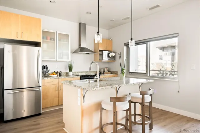 a kitchen with stainless steel appliances granite countertop a refrigerator a stove a sink and white cabinets with wooden floor