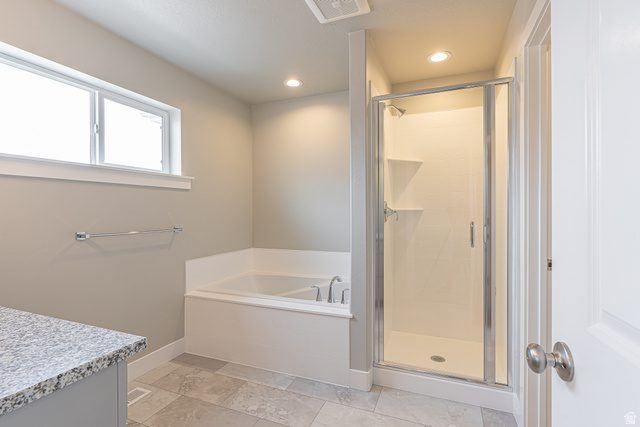 2257 South 1090 West, Unit 74 Nibley, UT 84321 - Photo 17 of 40 Bathroom featuring a built-in soaking tub, a glass-enclosed shower with integrated shelving, and a vanity with a granite-style countertop