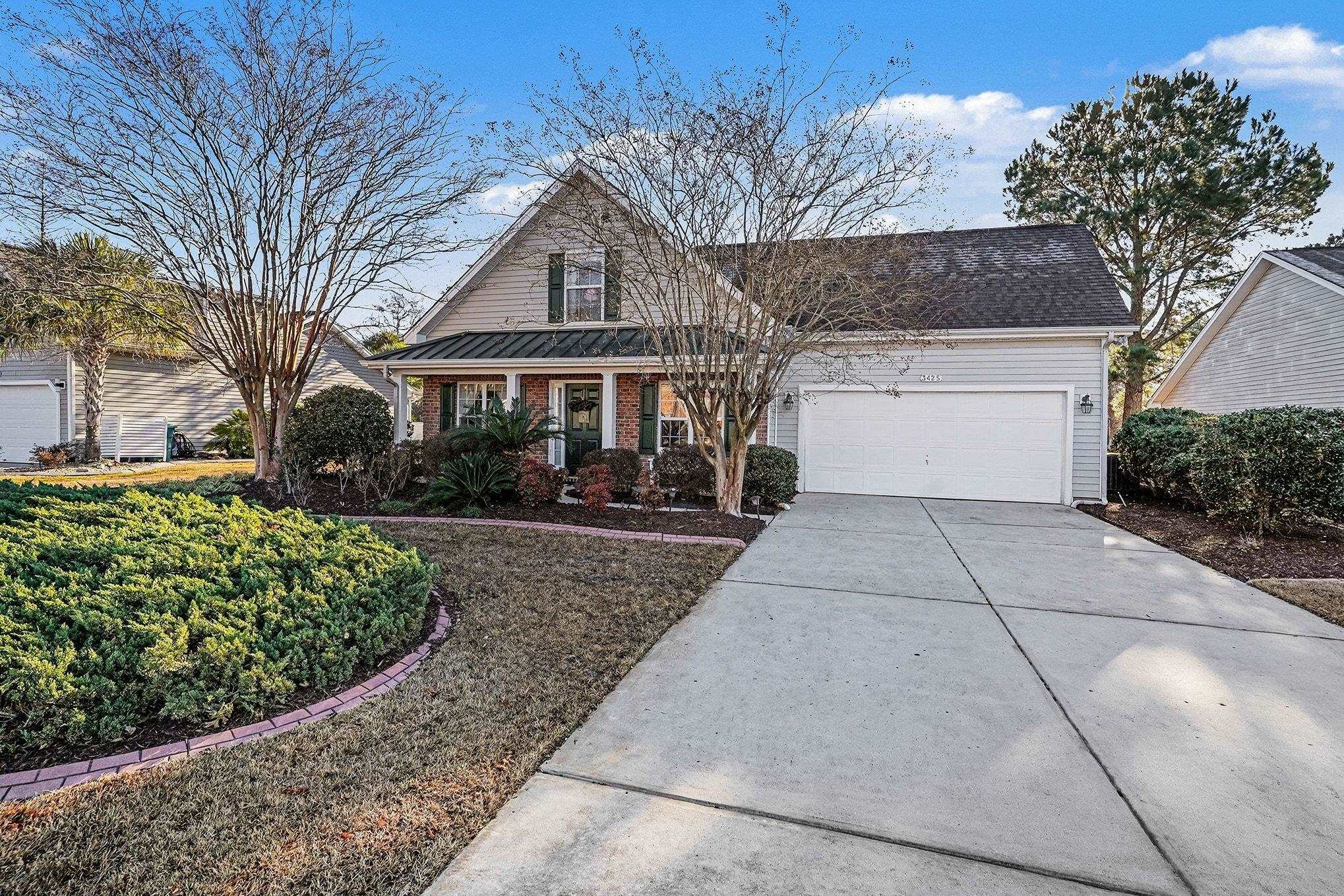 View of front facade featuring covered porch, brick siding, concrete driveway, and a garage