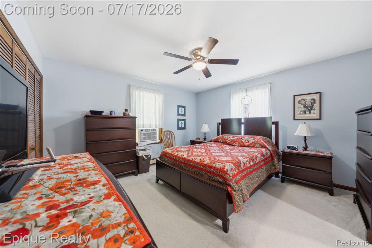 555 East Square Lake Road Troy, MI 48085 - Photo 19 of 48 Bedroom featuring wall-to-wall carpeting, light blue wall paint, a window with sheer curtains, a ceiling fan with integrated lighting, and louvered bifold closet doors