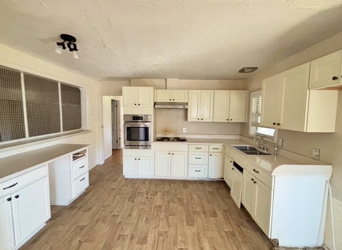 2208 Marshall Street Pasadena, TX 77506 - Photo 8 of 24 a large kitchen with granite countertop a stove top oven a sink dishwasher and white cabinets with wooden floor