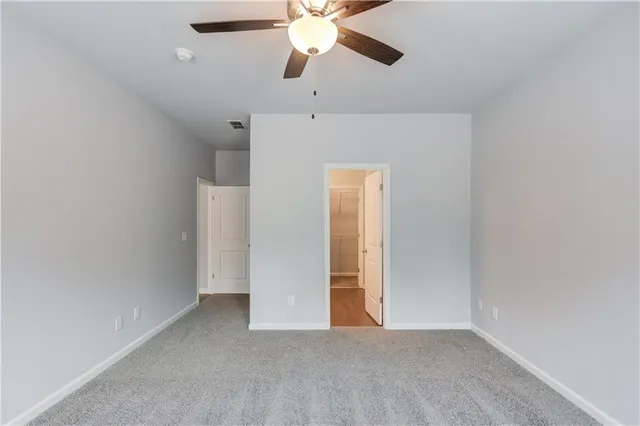 a view of an empty room and chandelier fan