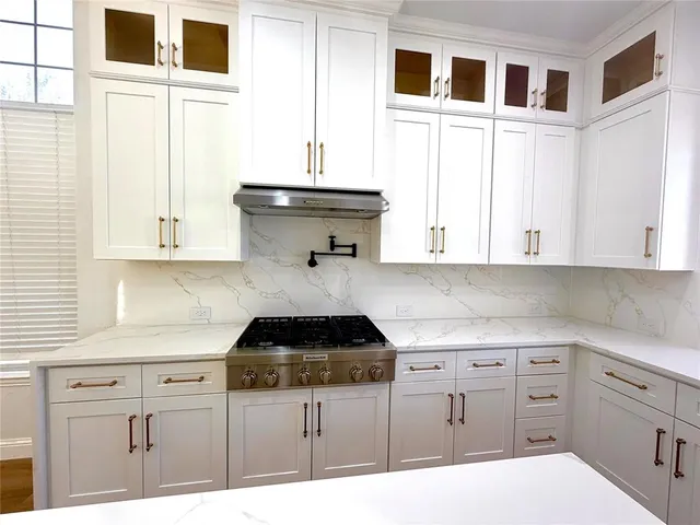 a kitchen with white cabinets and sink