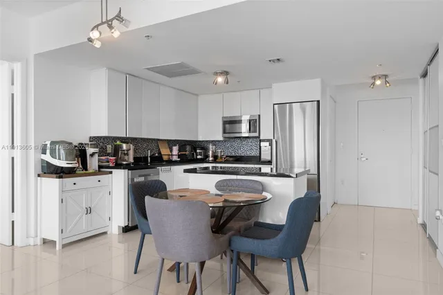 a kitchen with granite countertop a refrigerator a stove a sink a dining table and chairs