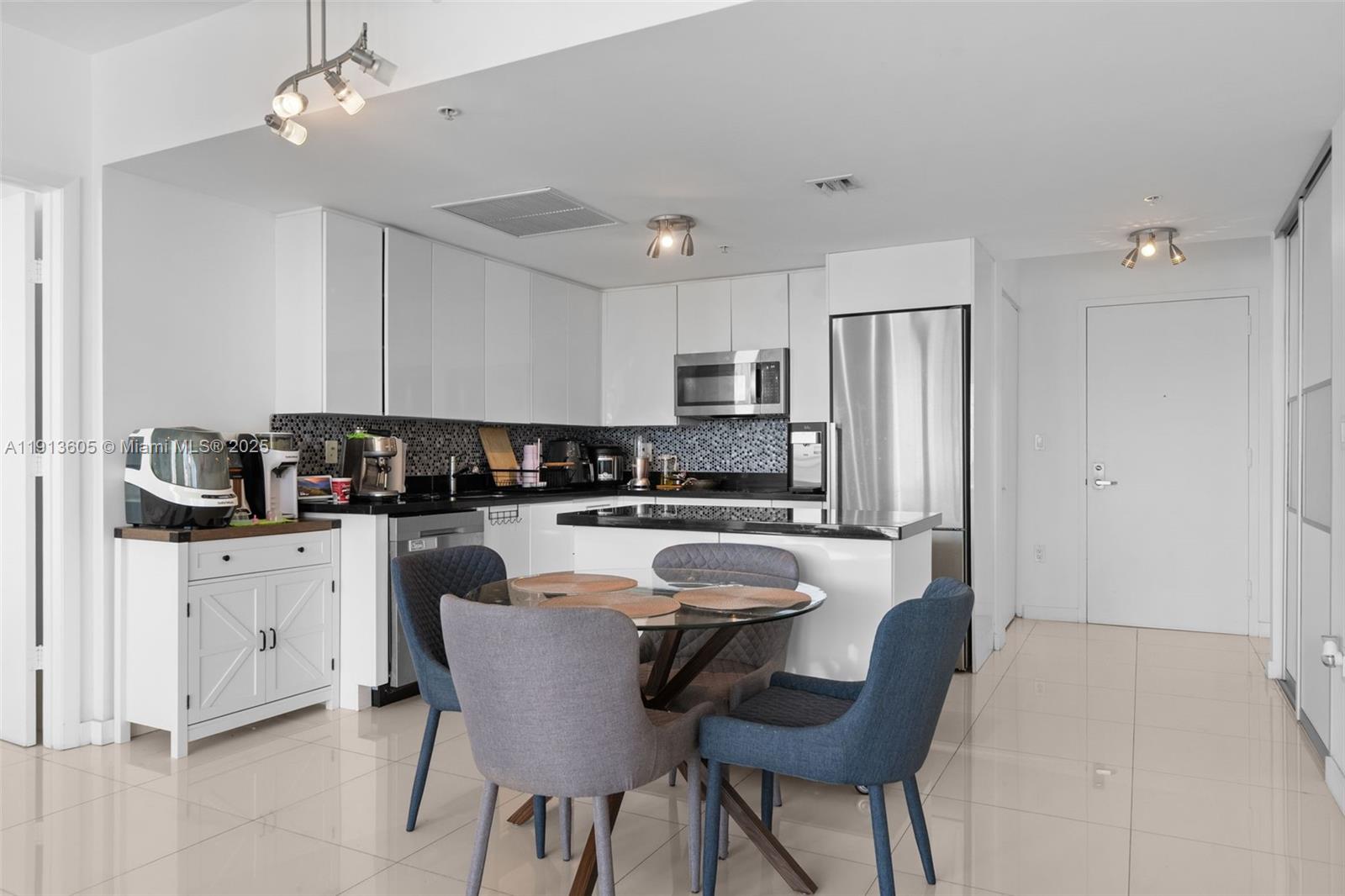92 Southwest 3rd Street, Unit 4403 Miami, FL 33130 - Photo 3 of 28 a kitchen with granite countertop a refrigerator a stove a sink a dining table and chairs