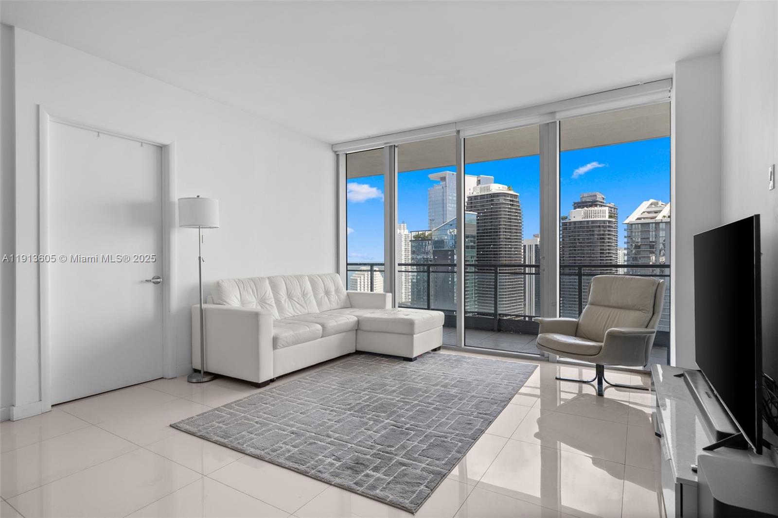 92 Southwest 3rd Street, Unit 4403 Miami, FL 33130 - Photo 10 of 28 a living room with furniture a flat screen tv and a floor to ceiling window