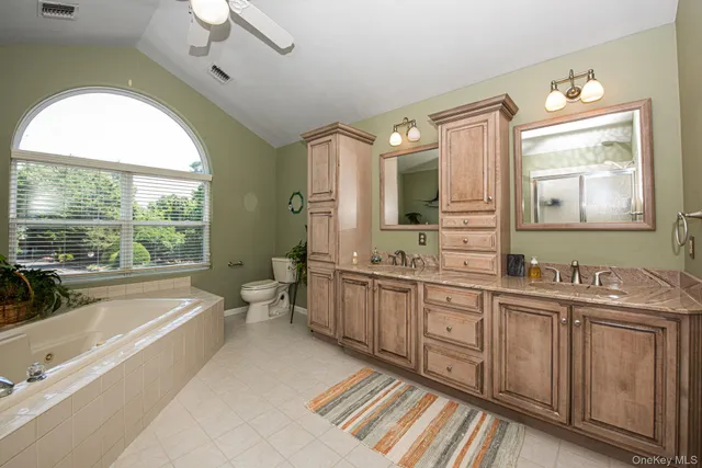 a spacious bathroom with a double vanity sink a large mirror and a bathtub next to a window