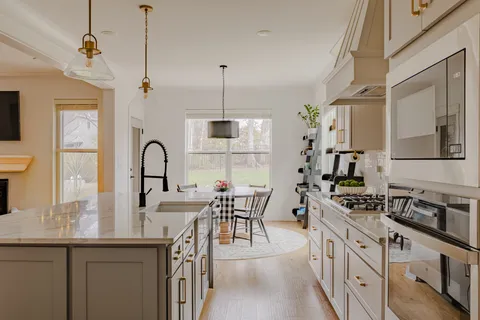 a kitchen with stainless steel appliances granite countertop a dining table chairs and white cabinets