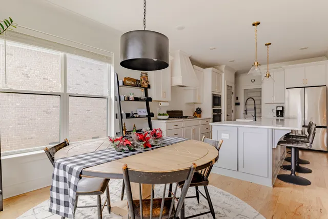 a kitchen with stainless steel appliances granite countertop a dining table chairs and white cabinets