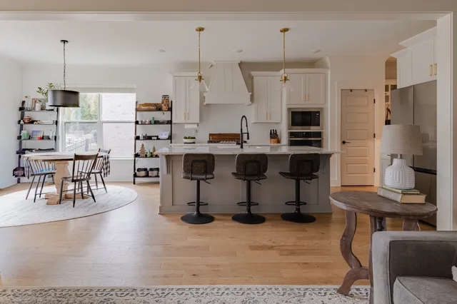a kitchen with stainless steel appliances kitchen island granite countertop a table chairs and a view of living room