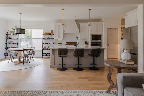 a kitchen with stainless steel appliances kitchen island granite countertop a table chairs and a view of living room