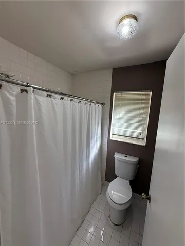 a white toilet sitting next to a small window