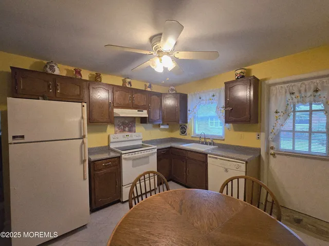 a kitchen with refrigerator a sink cabinets and wooden floor