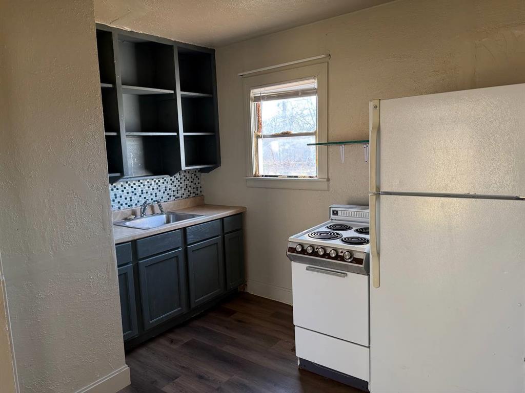 814 Tennessee Street Graham, TX 76450 - Photo 8 of 10 a kitchen with a refrigerator and a stove top oven