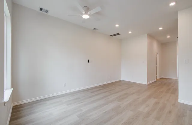a view of an empty room with wooden floor and a window