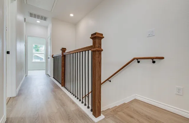an empty room with wooden floor and ceiling fan