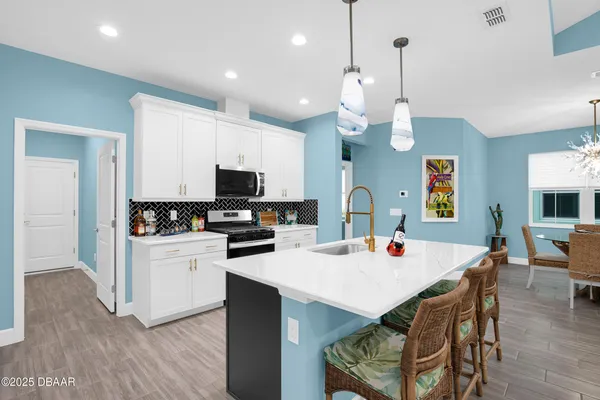 a kitchen with a dining table cabinets appliances and wooden floor