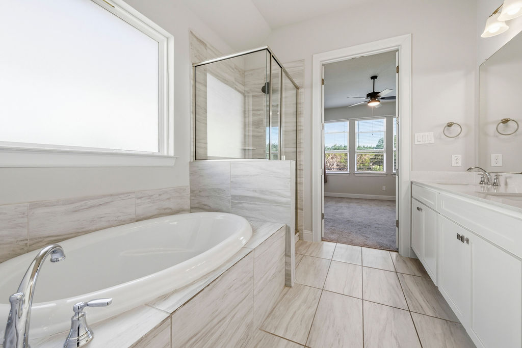 2032 Base Burner Path Leander, TX 78641 - Photo 16 of 34 Freestanding soaking tub with chrome fixtures, tiled surround, and frosted window