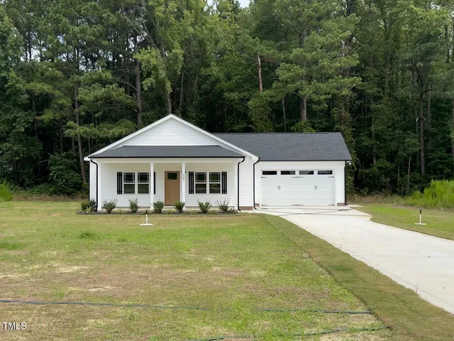 a front view of a house with a garden and trees