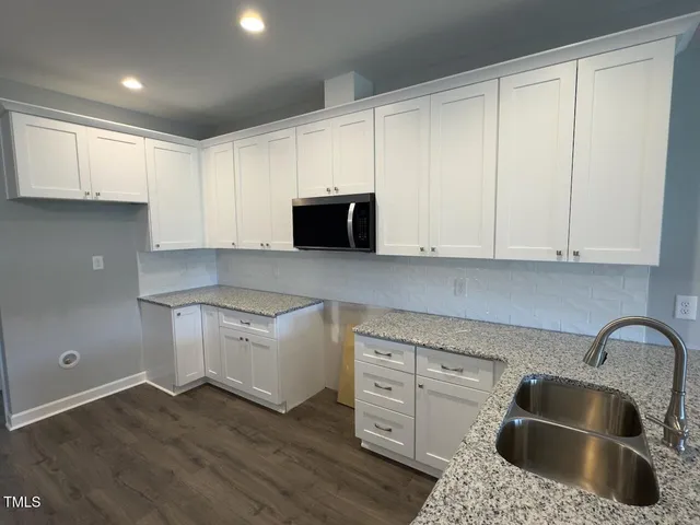 a kitchen with granite countertop white cabinets and sink