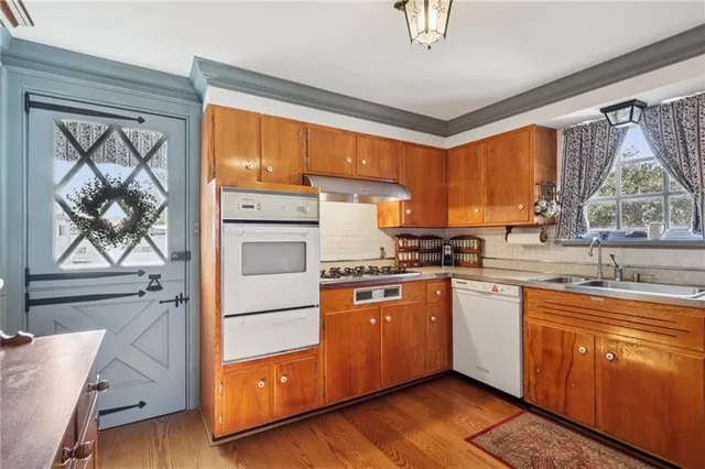 a kitchen with stainless steel appliances granite countertop a refrigerator a sink dishwasher a stove and white countertops with wooden floor