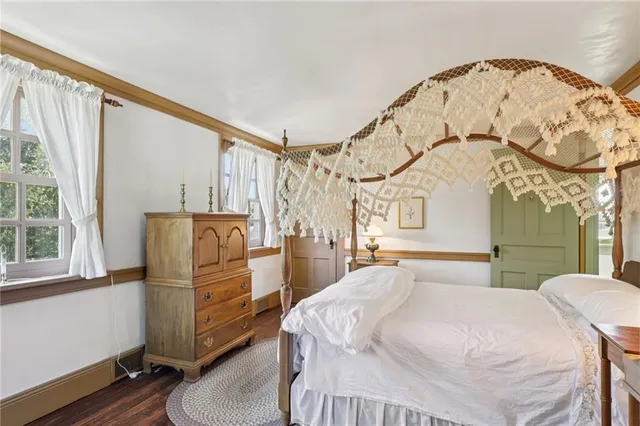 a bedroom with a bed a dresser and a large mirror next to a window