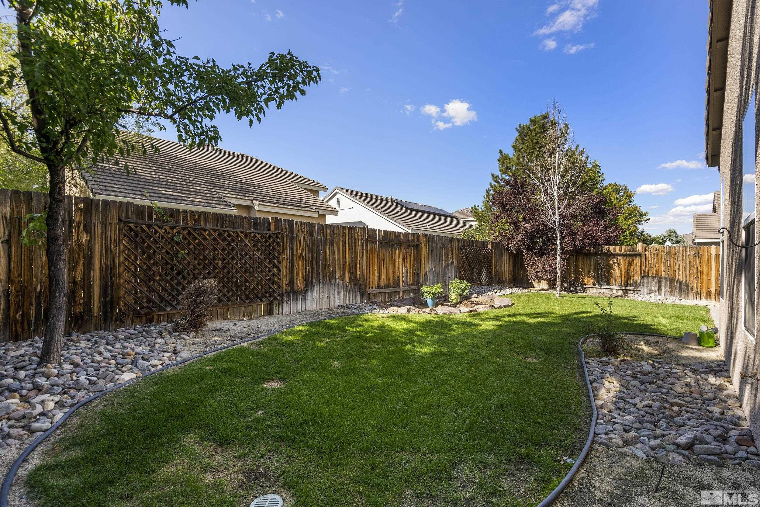 10245 Grizzly Hill Court Reno, NV 89521 - Photo 31 of 40 a backyard of a house with table and chairs plants and large tree