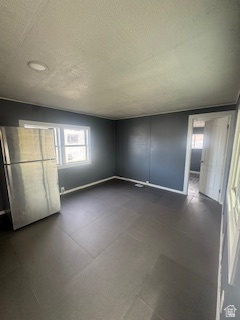 8155 South Redwood Road, Unit 96 West Jordan, UT 84088 - Photo 9 of 17 Unfurnished bedroom featuring freestanding refrigerator, multiple windows, and a textured ceiling