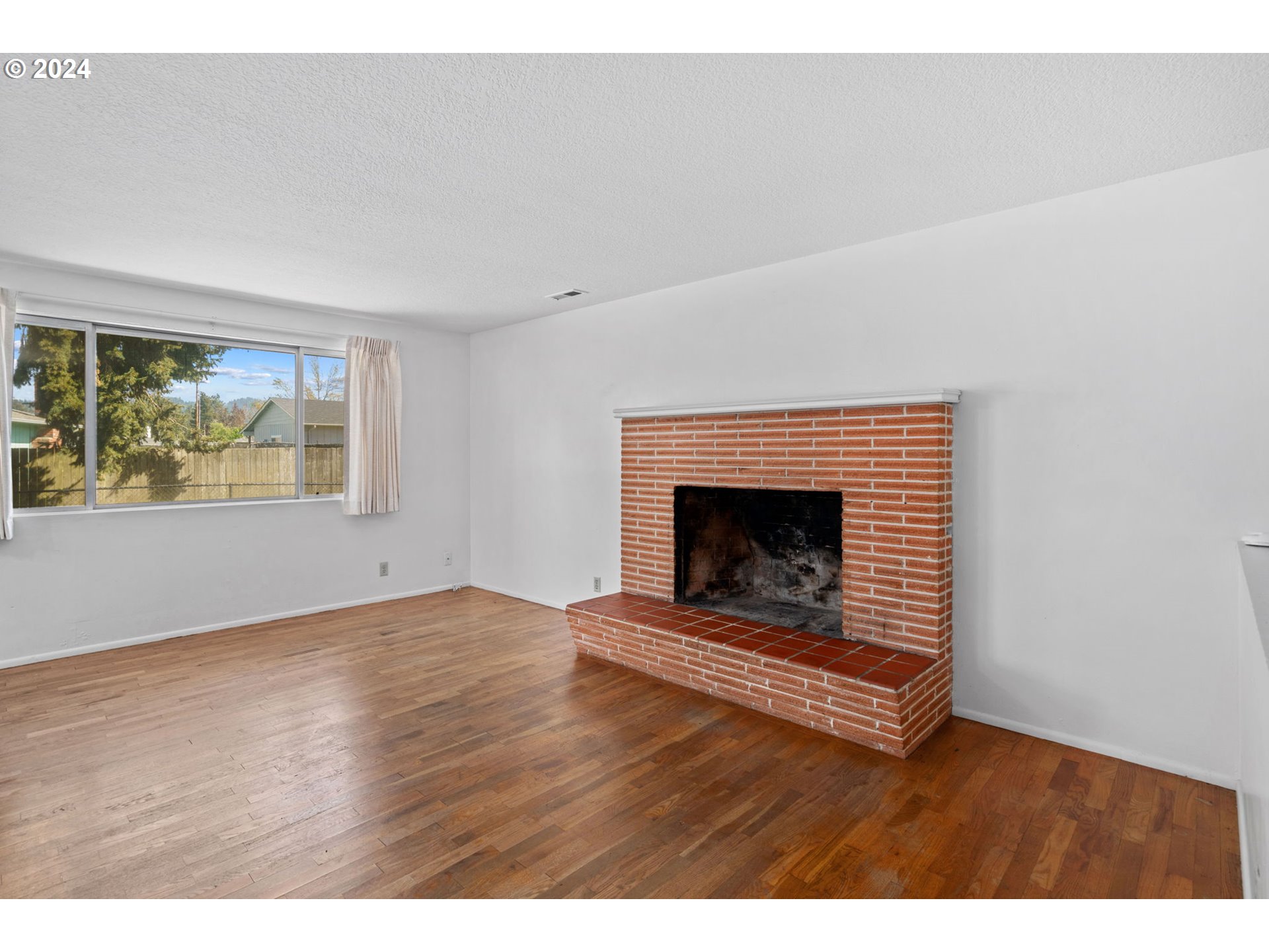 5246 E Street Springfield, OR 97478 - Photo 5 of 26 a view of an empty room with wooden floor fireplace and a window
