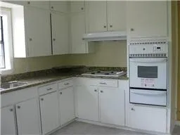 a kitchen with granite countertop white cabinets and white appliances
