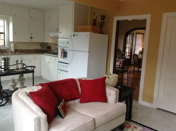 a living room with stainless steel appliances furniture a refrigerator and a window