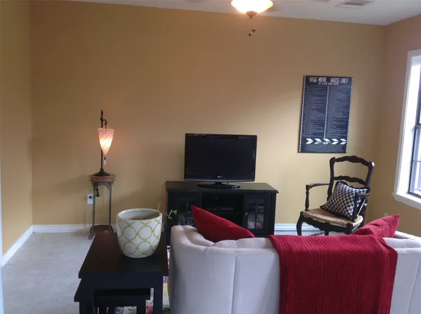 a living room with furniture a flat screen tv and a lamp
