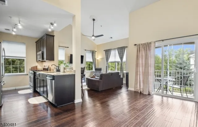 a room with kitchen island granite countertop lots of furniture and wooden floor