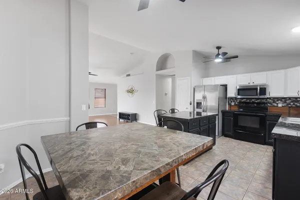 a kitchen with granite countertop a stove a sink a kitchen island with chairs and wooden floor