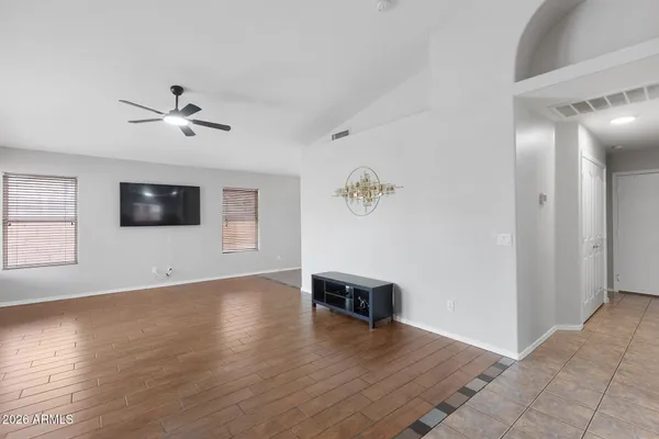 an empty room with wooden floor chandelier fan and windows
