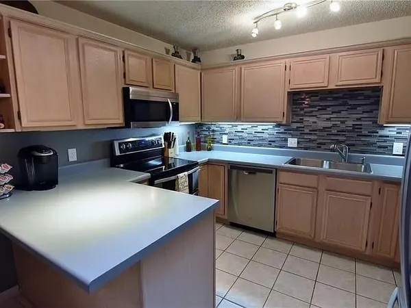 a kitchen with stainless steel appliances a sink a stove top oven a counter space and cabinets