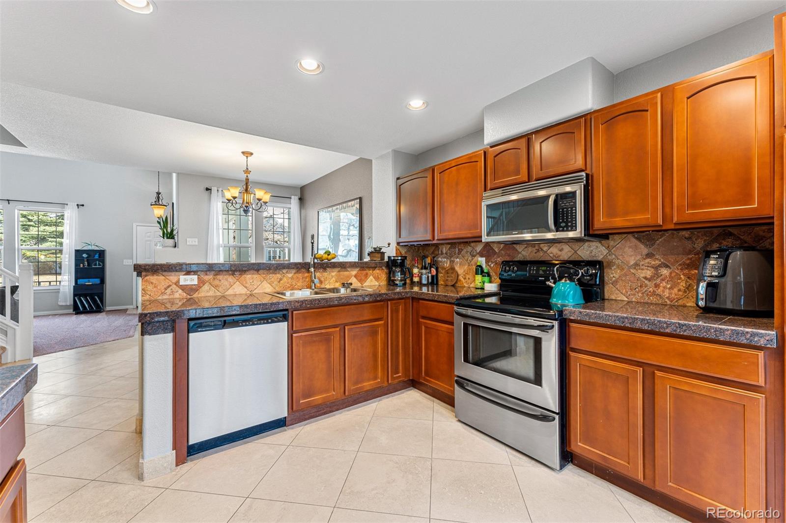 8300 Fairmount Drive, Unit 103 Denver, CO 80247 - Photo 13 of 34 a kitchen with stainless steel appliances granite countertop a stove top oven a sink dishwasher a dining table and chairs with wooden floor
