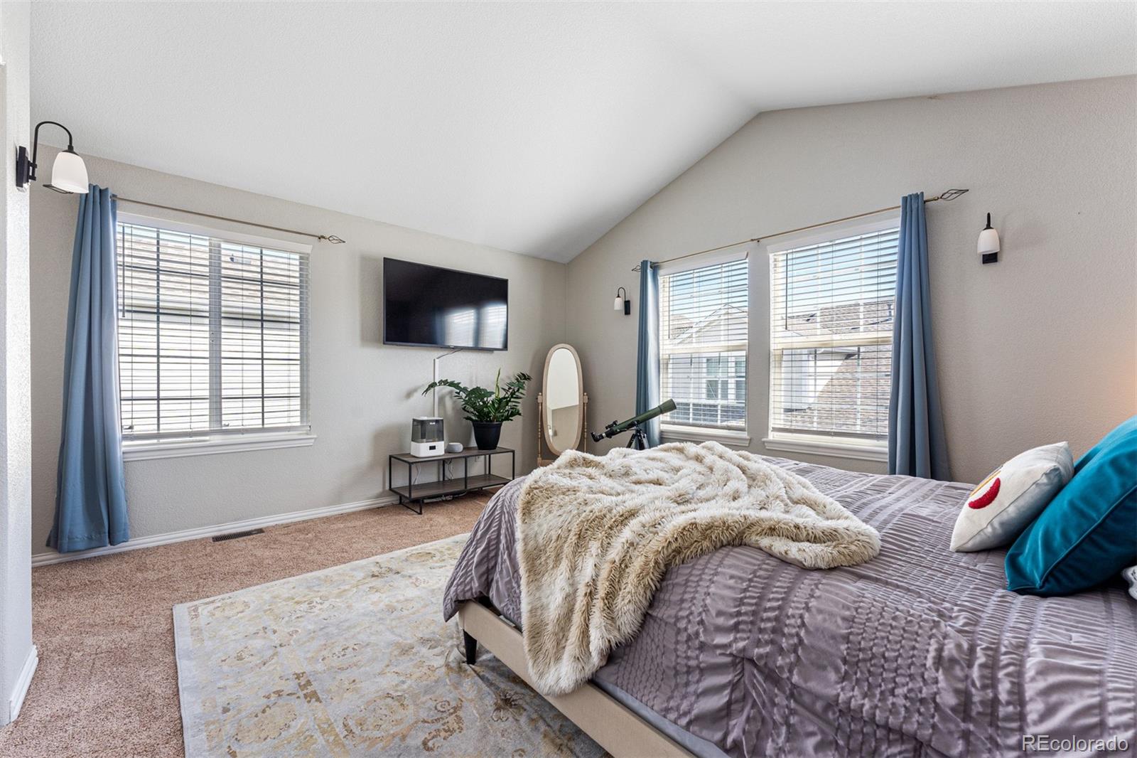 8300 Fairmount Drive, Unit 103 Denver, CO 80247 - Photo 17 of 34 a bedroom with a bed and a flat tv screen on the dresser