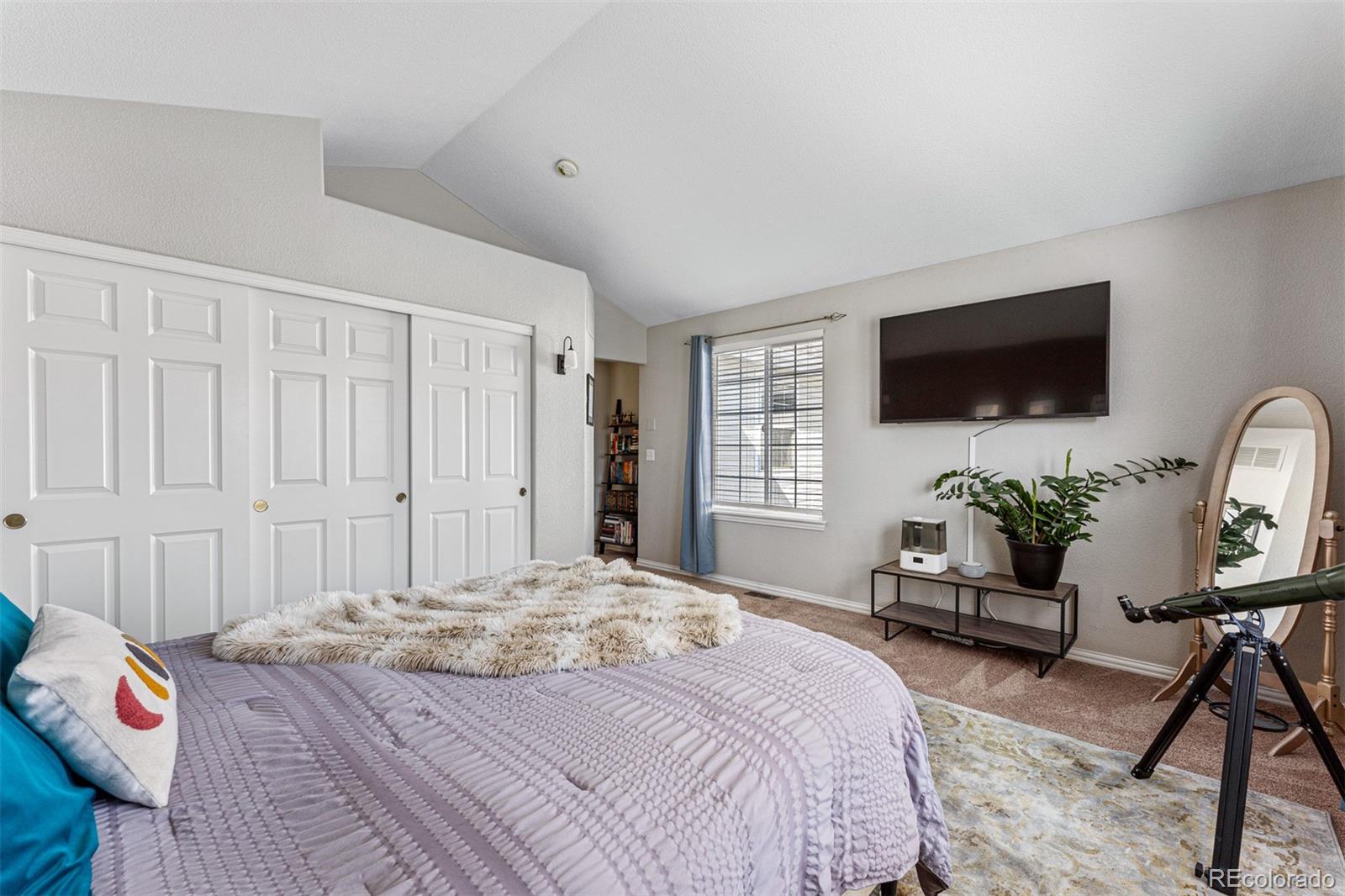 8300 Fairmount Drive, Unit 103 Denver, CO 80247 - Photo 18 of 34 a bedroom with a bed a flat screen tv and a couch