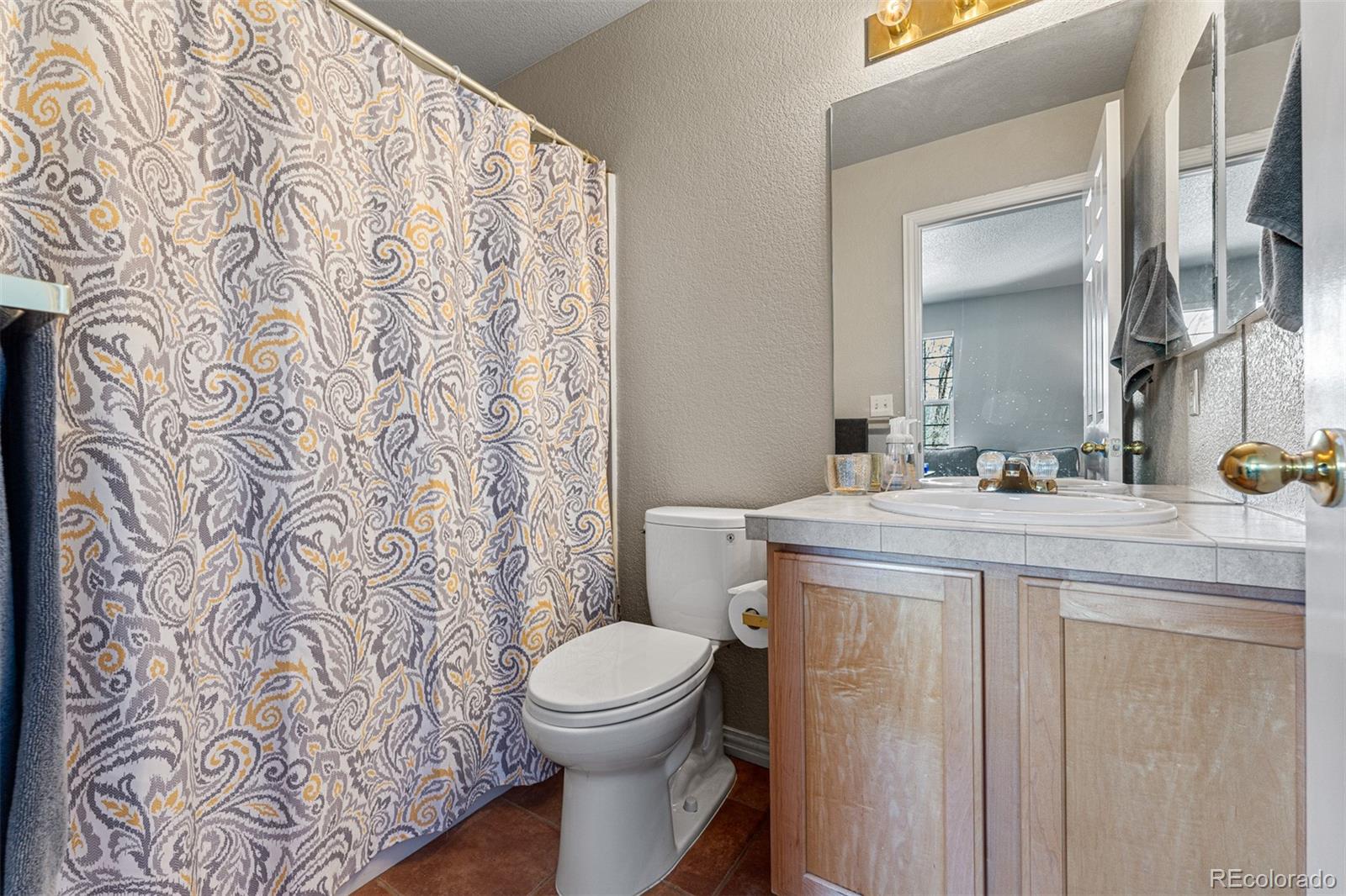 8300 Fairmount Drive, Unit 103 Denver, CO 80247 - Photo 24 of 34 a bathroom with a granite countertop toilet sink and mirror