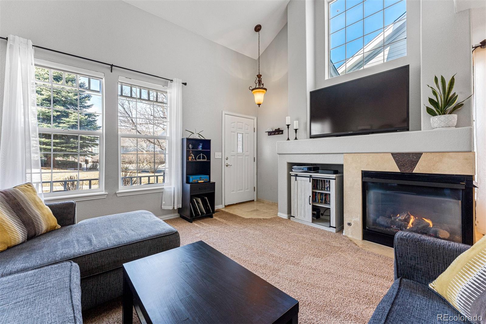 8300 Fairmount Drive, Unit 103 Denver, CO 80247 - Photo 7 of 34 a living room with furniture a flat screen tv and a fireplace