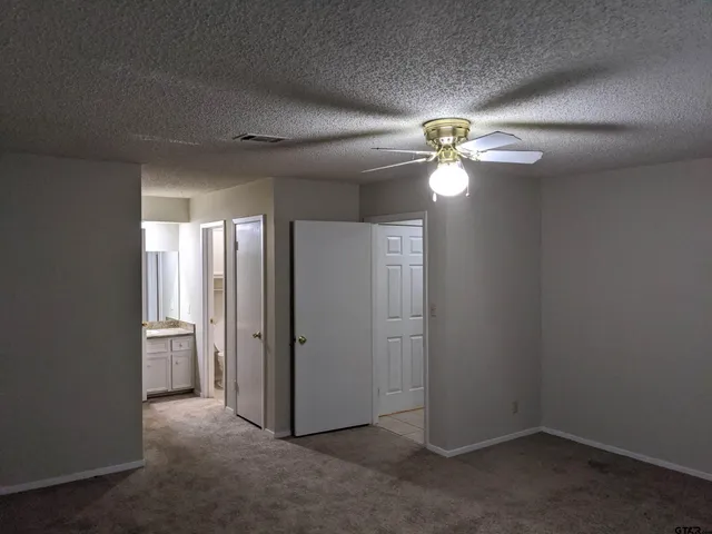 an empty room with chandelier fan and windows