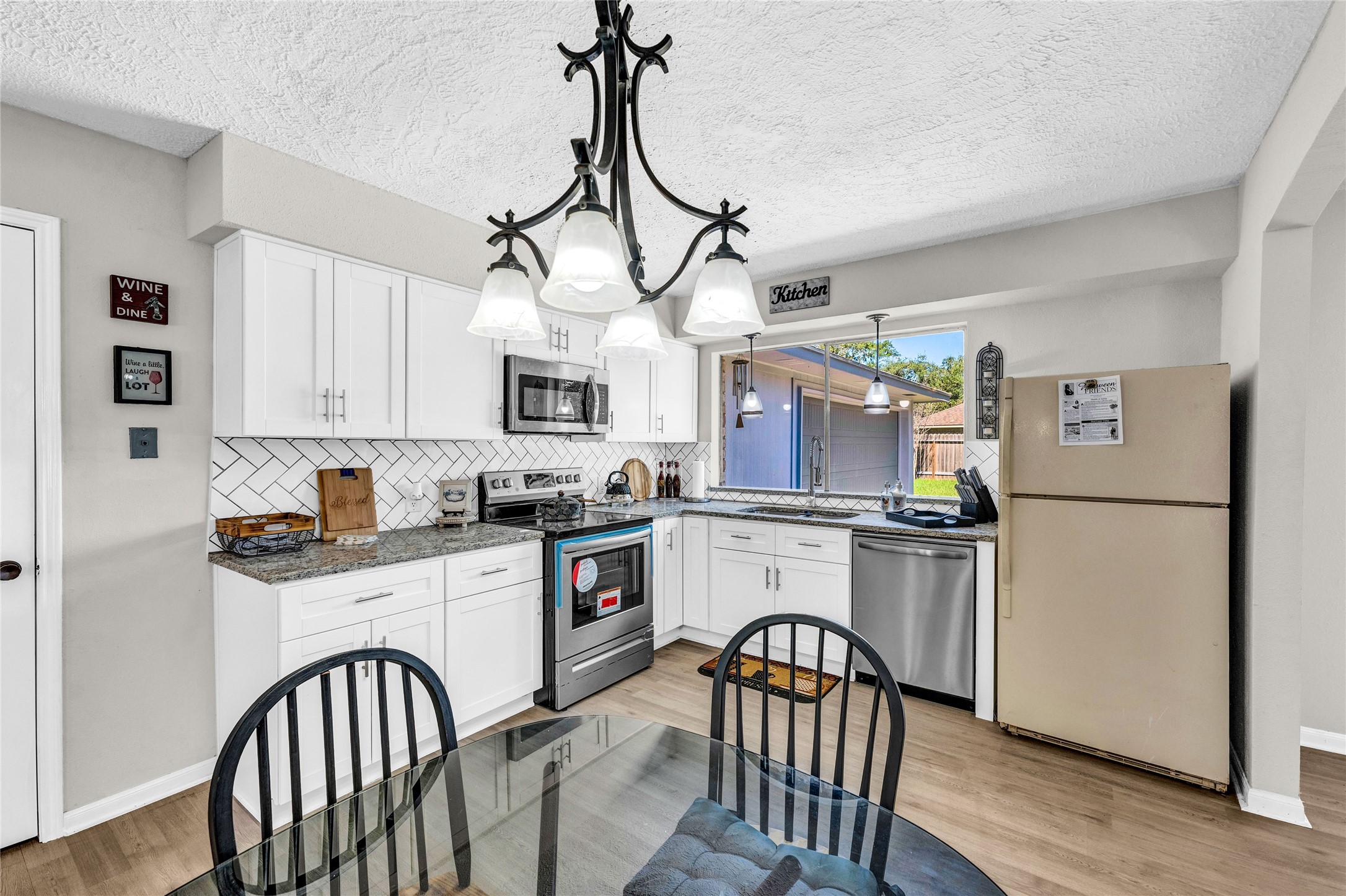 2705 Parrott Avenue Rosenberg, TX 77471 - Photo 14 of 27 a kitchen with stainless steel appliances granite countertop a refrigerator a stove a sink dishwasher and white cabinets with wooden floor