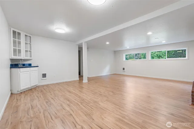 a view of an empty room with kitchen and a window