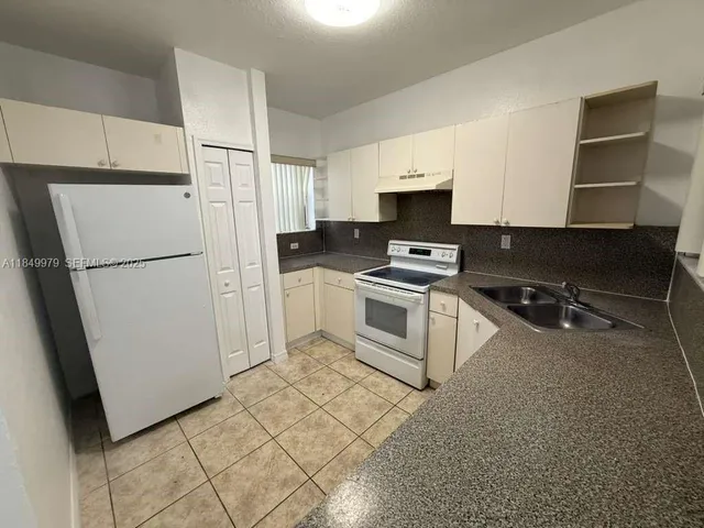 a kitchen with a refrigerator a stove top oven a sink and cabinets