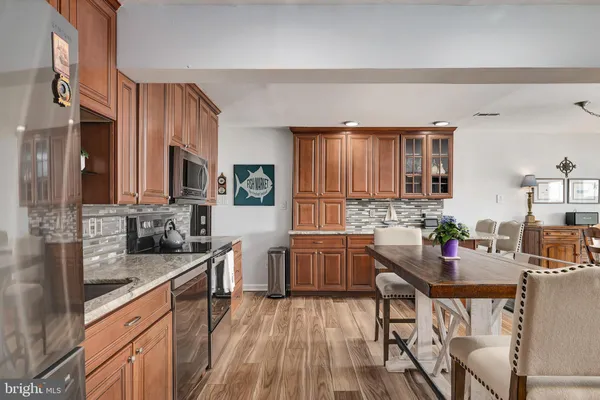 a kitchen with granite countertop a table chairs stove and wooden floor