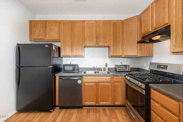 a kitchen with a refrigerator a stove a sink and cabinets